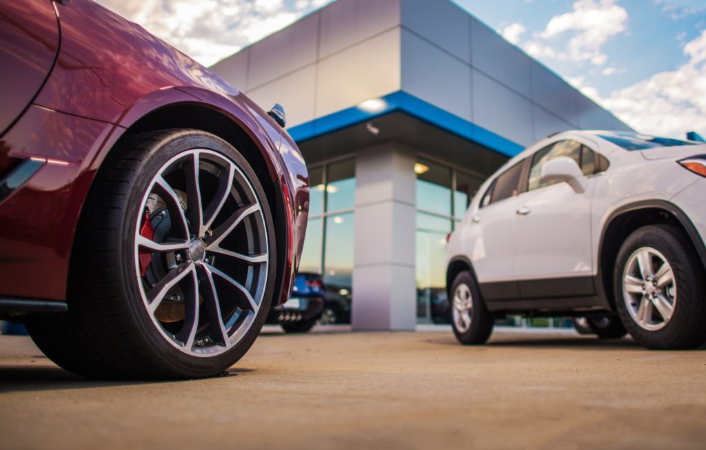 Automotive Dealership Store. New and Pre Owned Vehicles in Front of the Showroom Building.