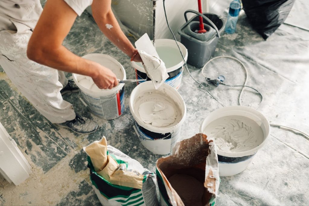 A man painting a room white with a paint roller.