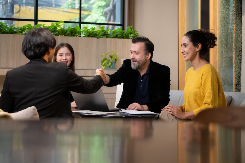 a man shaking hands with a woman in a room with a laptop