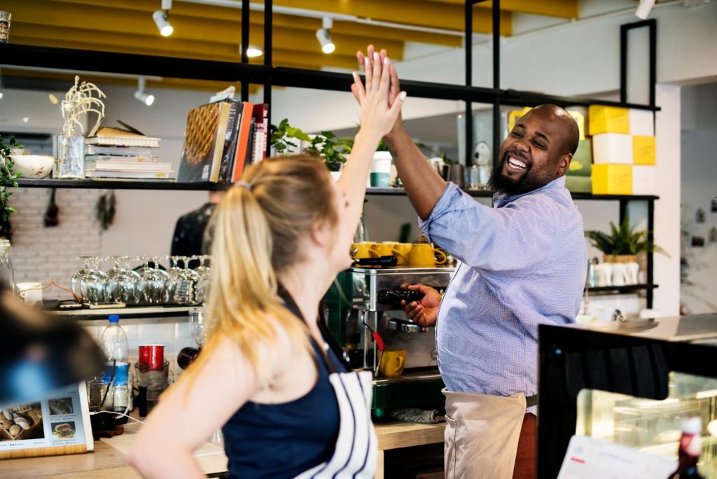 Man and woman joyfully high-fiving at a dining table.