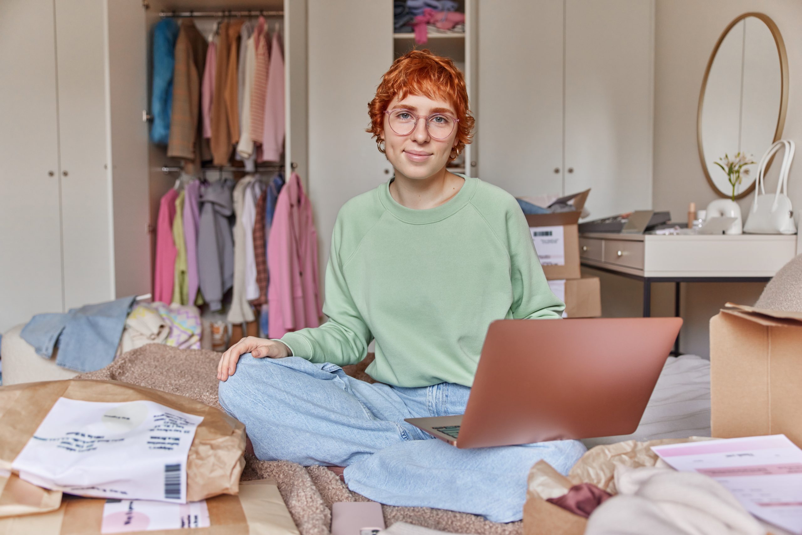 a woman sitting on the bed with a laptop