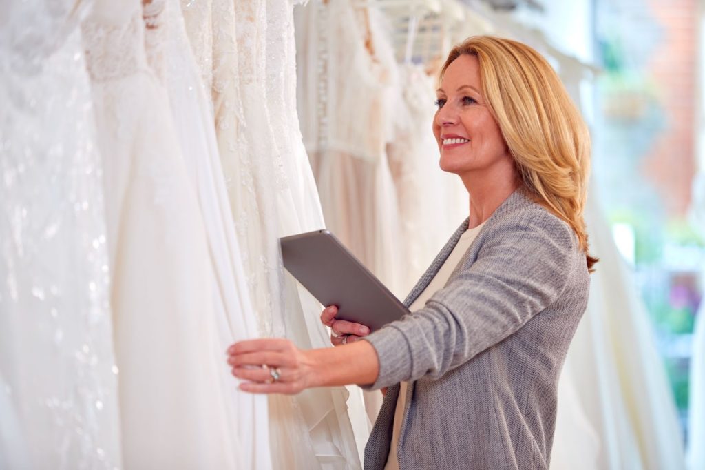 Lady browsing through beautiful bridal dresses in store.