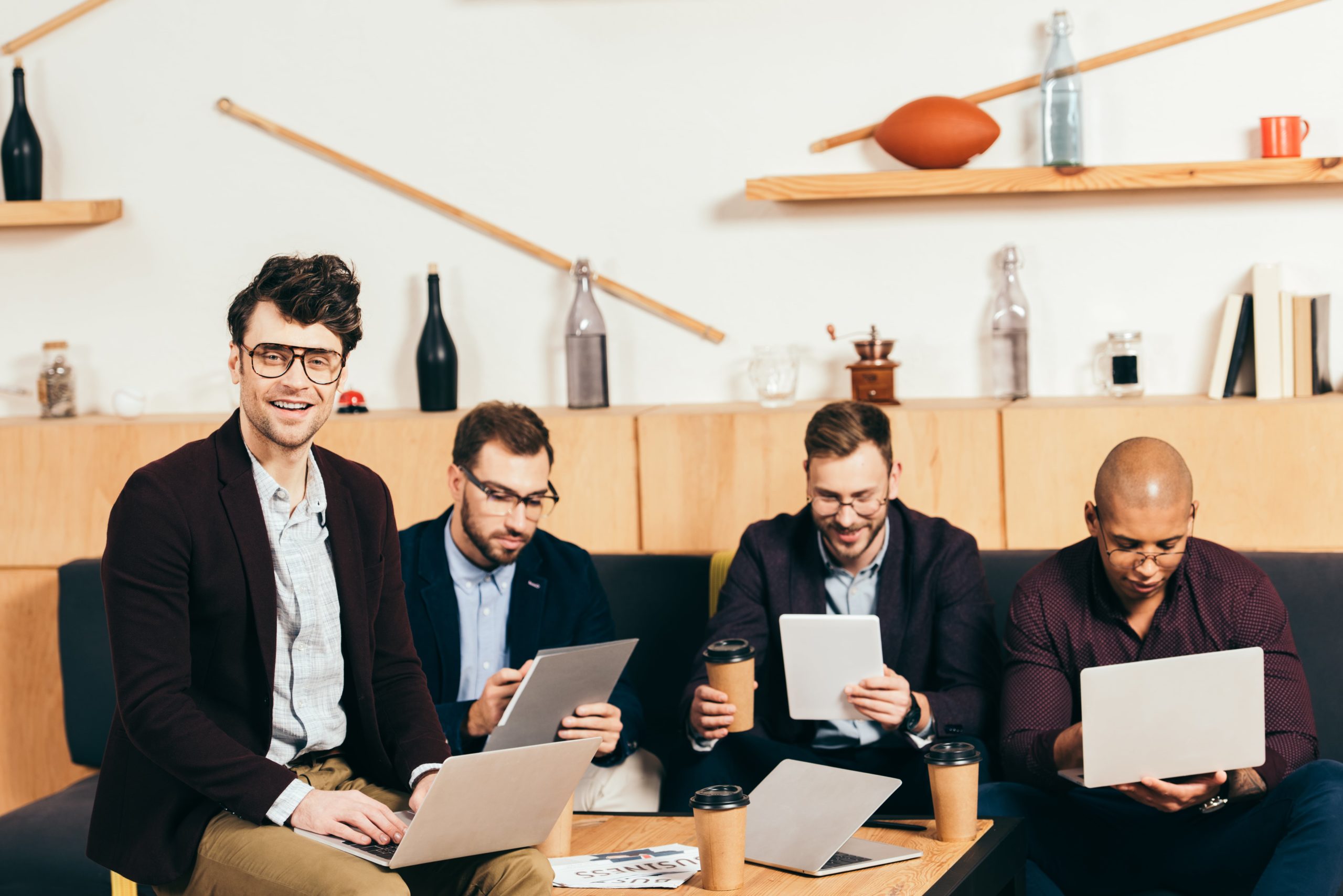 a group of men sitting on a couch with laptops