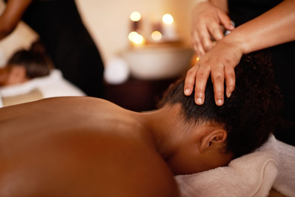 a person's hands massaging a man's head