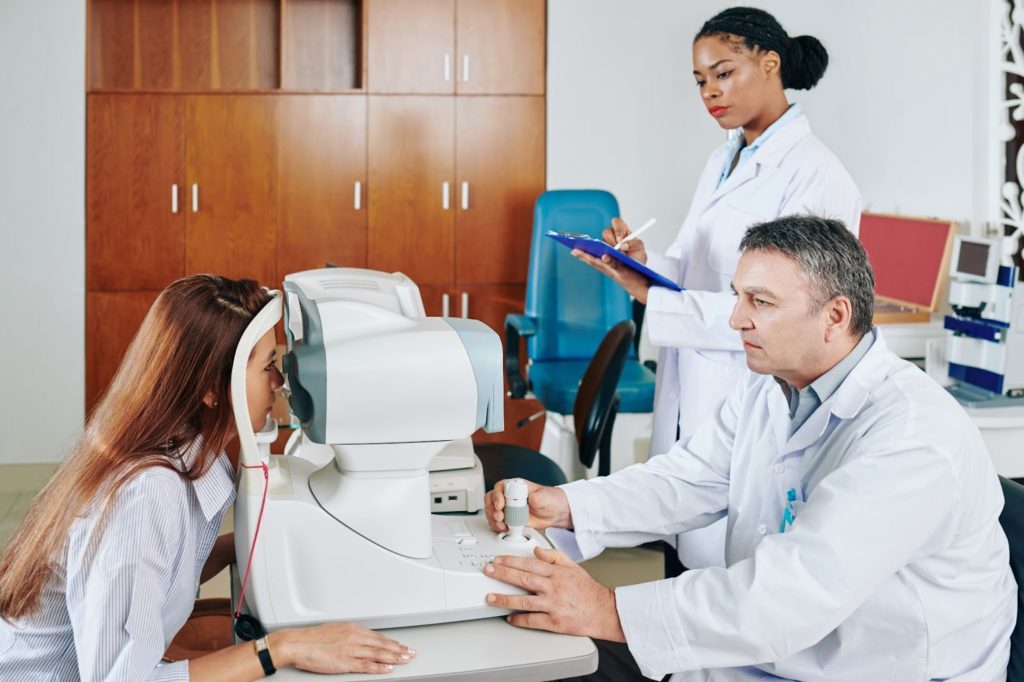 a group of people in lab coats looking at a woman's eye