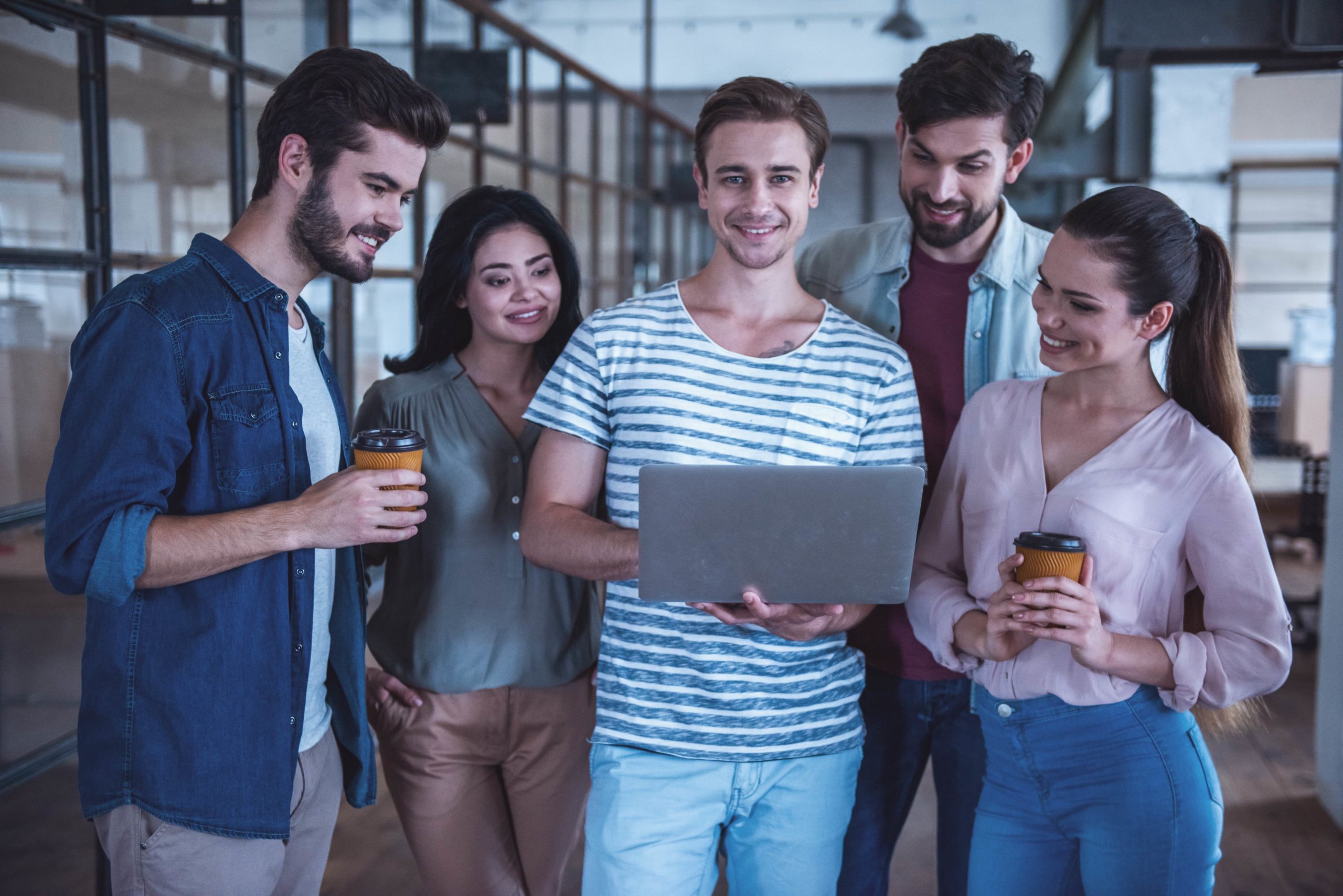 a group of people standing around a laptop