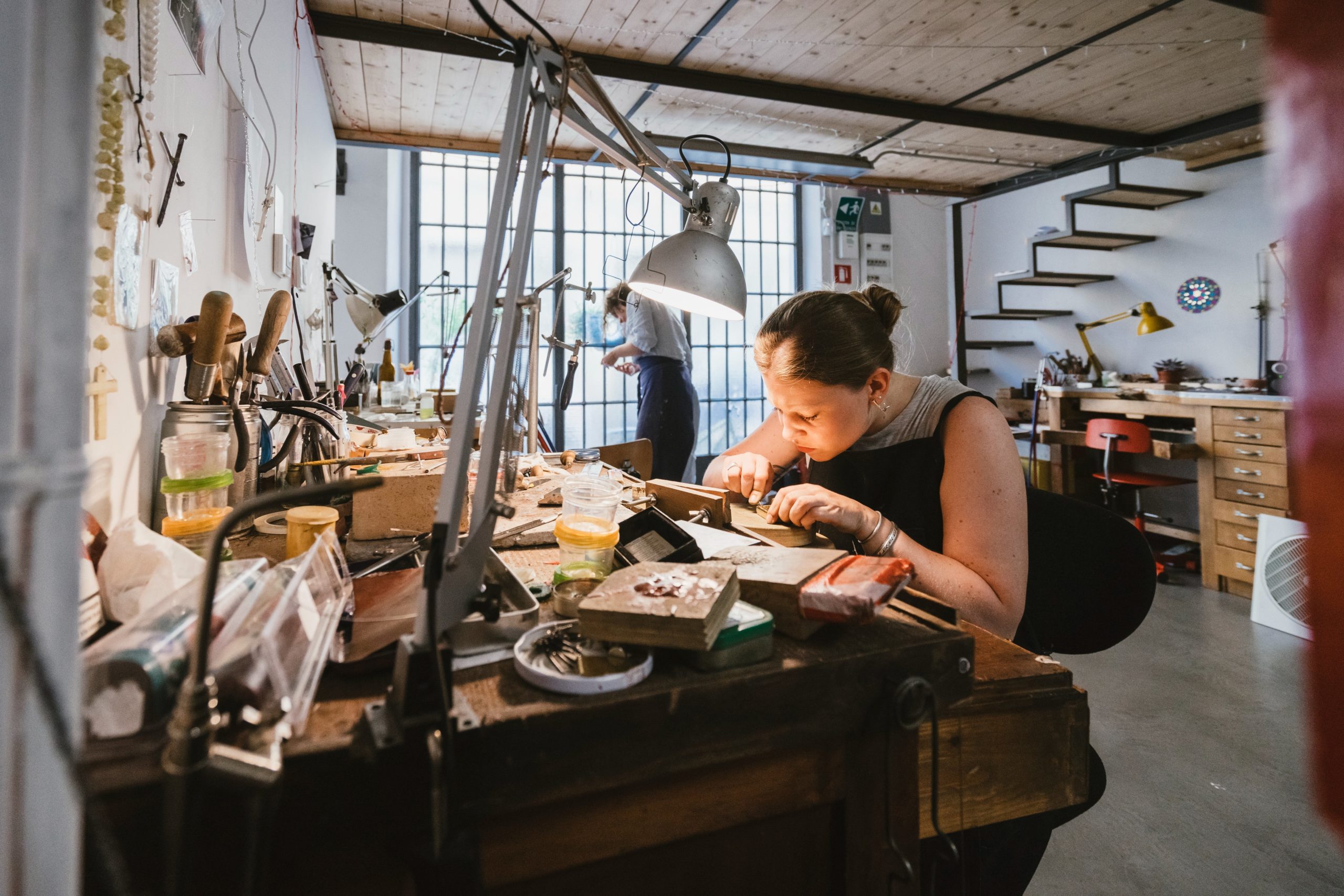 a woman working on a piece of wood in a workshop