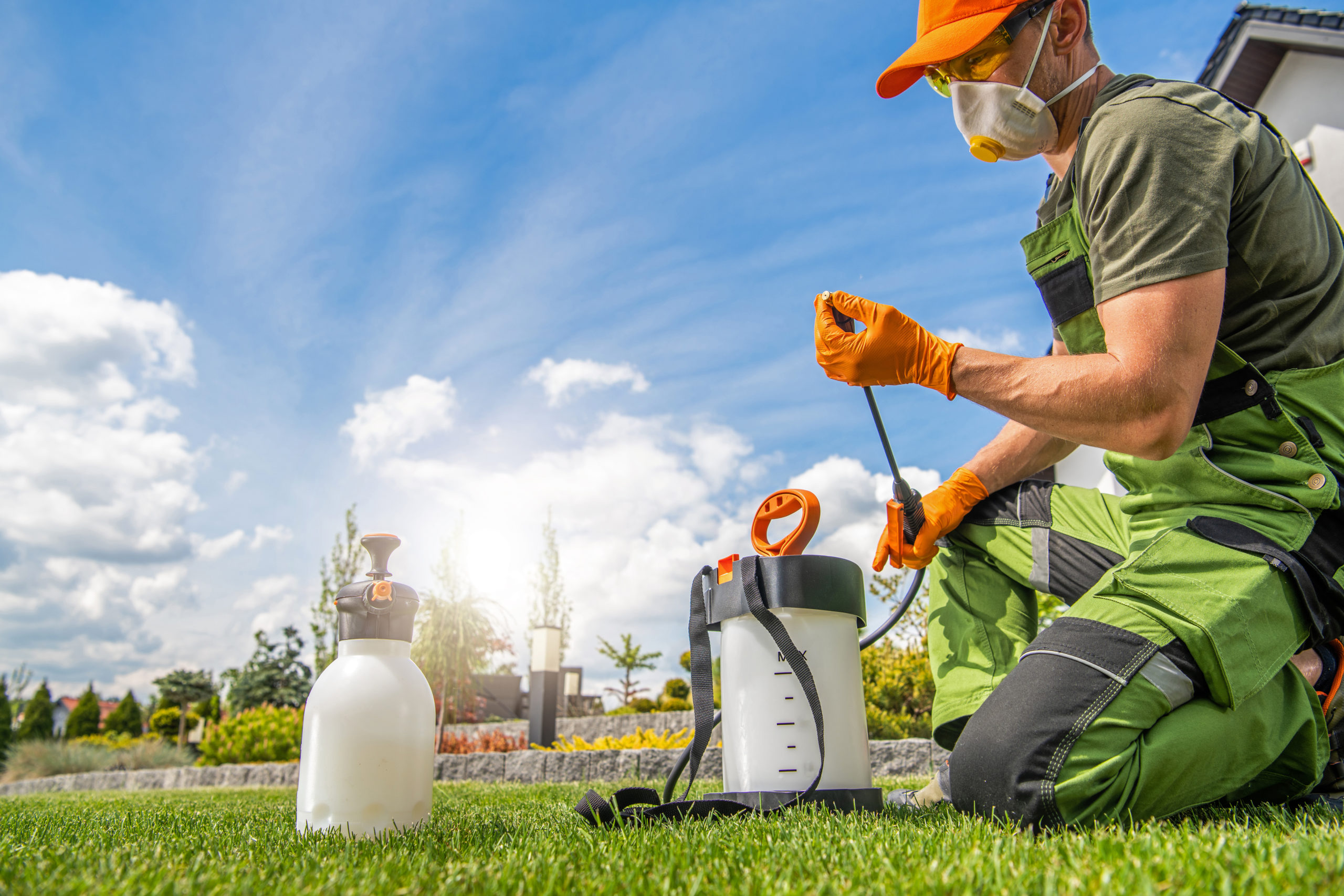 Caucasian Worker in His 40s Preparing Pest Control Spraying Equipment. Spring Garden Maintenance Theme.