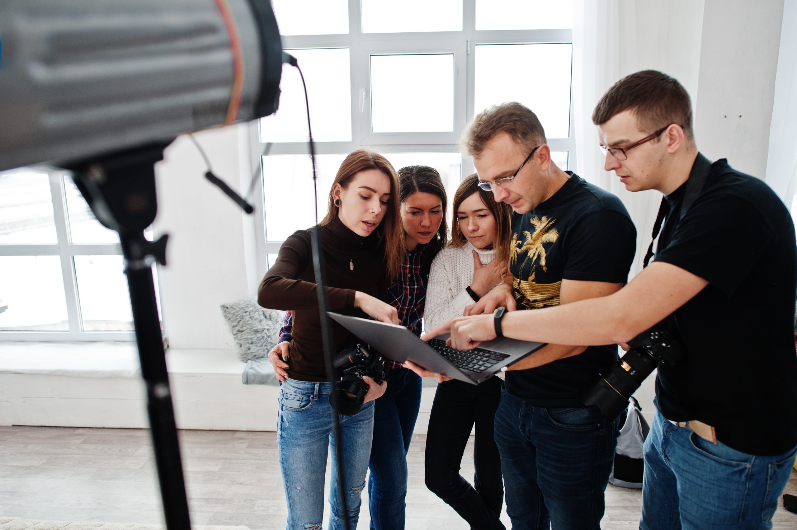 A diverse group of individuals gathered around a laptop, engrossed in what they see on the screen.