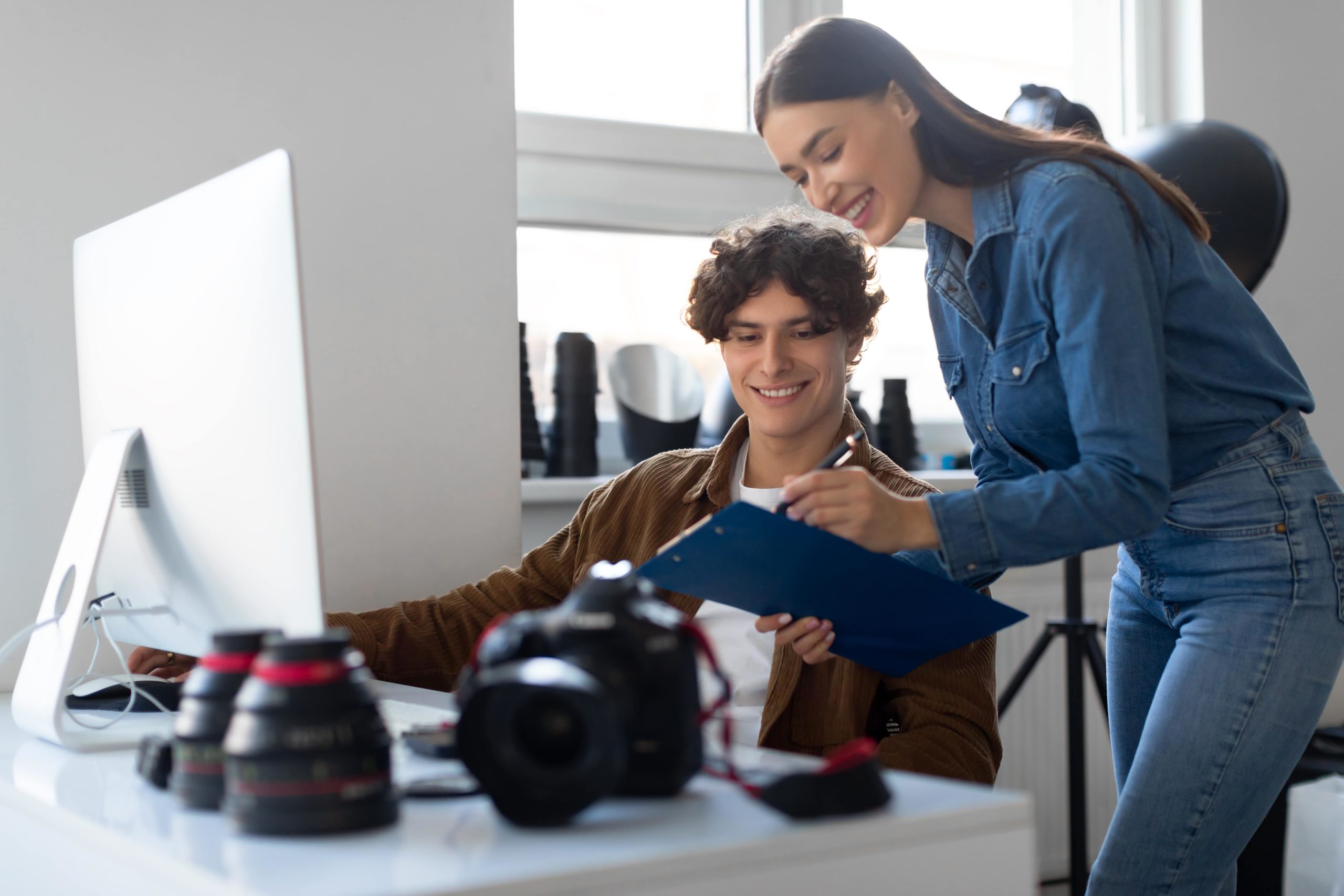 A man and woman looking at a computer screen, discussing work together.