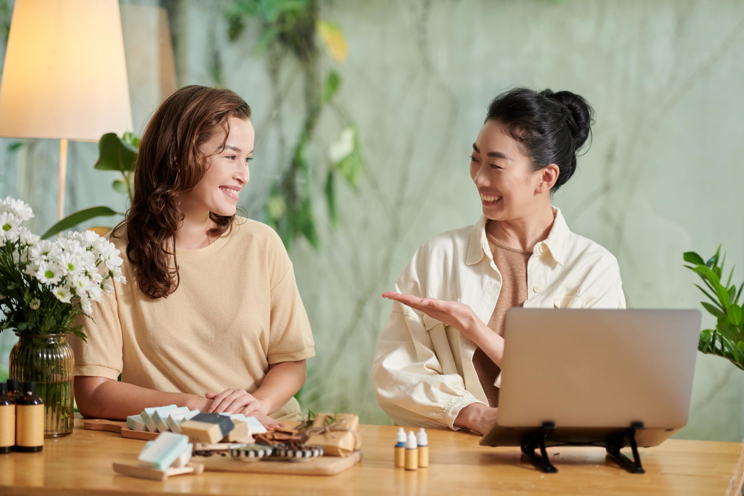 a couple of women sitting at a table looking at a laptop