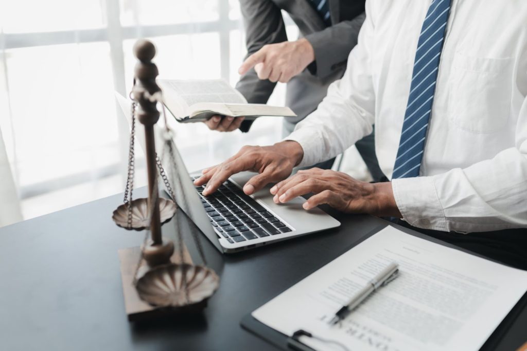 Two professionals in business attire collaborating on a laptop, engaged in lawfirm services.