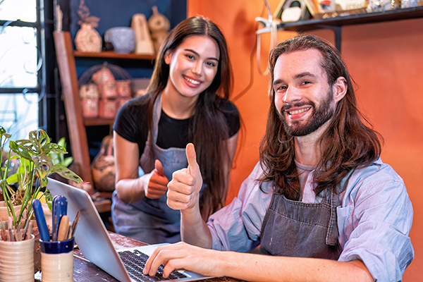 Women and man own pottery business use laptop happy smiling successful running business